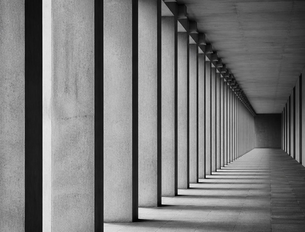 Black and white photograph of a repeating concrete colonnade